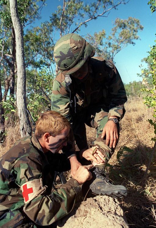 A medic checks an injury on the leg of a soldier from 4th… — NARA and ...