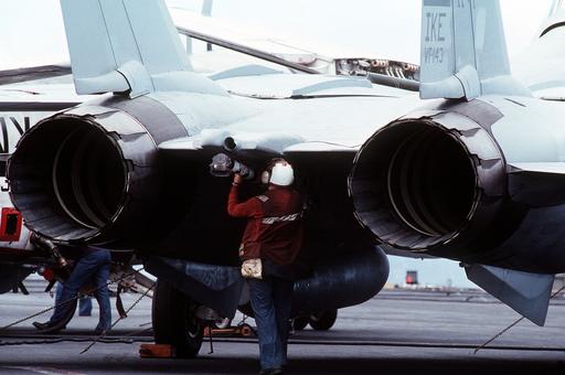A plane captain inspects the tailhook of an F-14A Tomcat… — NARA