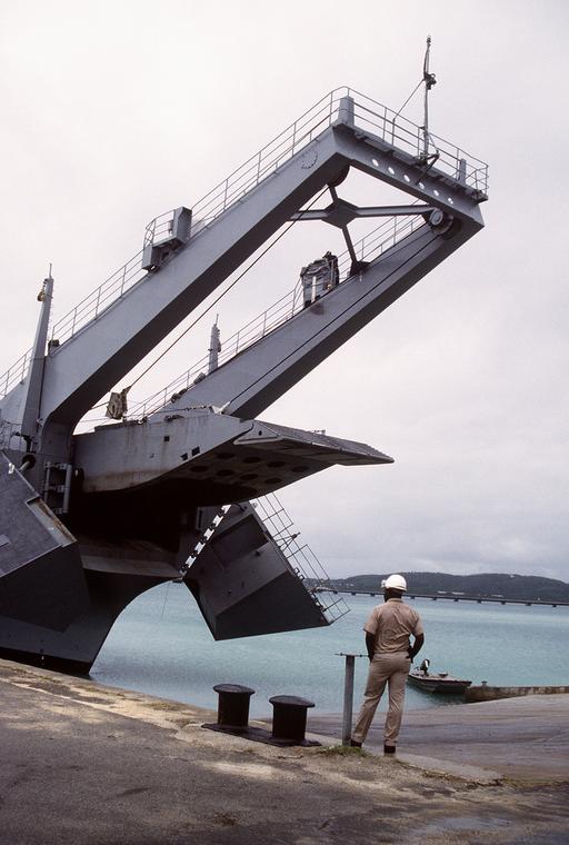 A crewman watches from the pier as the bow ramp of the… — NARA and ...