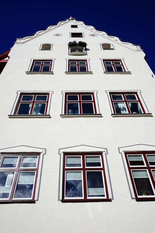 A tall white building with windows and a clock Home facade ulm building ...