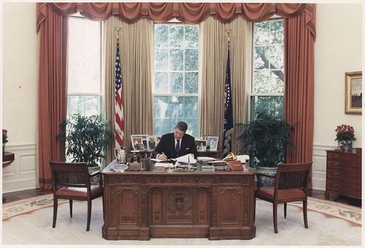 Photograph of President Reagan working at his desk in the Oval Office ...