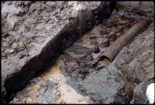 Archaeological dig shows the original palm log wall buried deep in the mud. (558e19b9-36da-48b0-a93e-dfff6374e610), archaeological dig, excavation, palm log, wall, mud, preservation, artifact, historical, site